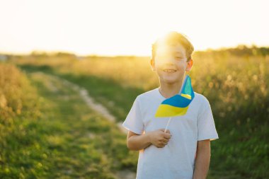 Ukrayna 'nın Bağımsızlık Günü. Ukrayna 'nın sarı ve mavi bayrağını taşıyan beyaz tişörtlü çocuk. Ukrayna bayrağı. Anayasa günü. Ukrayna 'nın yanında dur ve Kaydet