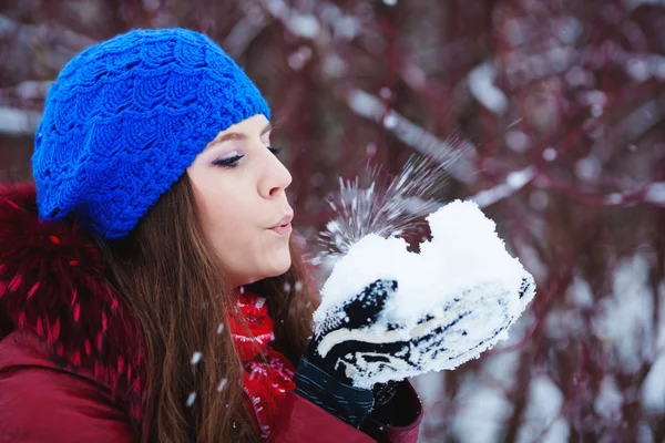 A Girl Wearing Warm Winter Clothes And Hat Blowing Snow In Winte — Stock Photo, Image