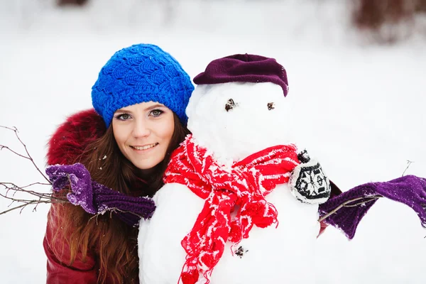 Jovem mulher construção boneco de neve no jardim — Fotografia de Stock