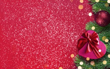 Kırmızı arka plan, köknar dalları, ışıklar ve hediye kutusu. Noel süslemesi.