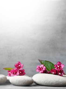 Yeşil yapraklı spa taşları ve gri arka planda çiçekler. Spa konsepti.