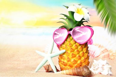 Sıcak kumsalda ananas, denizyıldızı ve güneş gözlüğü olan tropikal bir deniz. Kopya alanı ile seyahat ve tatil kavramı.