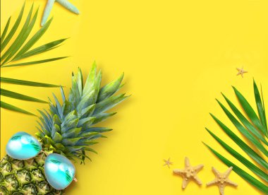 Yaz tasarımı konsepti. Sarı arka planda deniz yıldızı, ananas ve palmiye yapraklı tatil gezilerinin en üst manzarası..