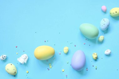 Paskalya kompozisyonu. Pastel mavi arka planda Paskalya yumurtası ve Paskalya tavşanı. Minimum Paskalya konsepti. Düz konum, üst görünüm, kopyalama alanı