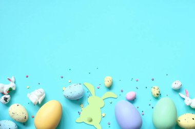 Paskalya kompozisyonu. Pastel mavi arka planda Paskalya yumurtası ve Paskalya tavşanı. Minimum Paskalya konsepti. Düz konum, üst görünüm, kopyalama alanı