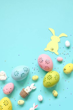 Paskalya kompozisyonu. Pastel mavi arka planda Paskalya yumurtası ve Paskalya tavşanı. Minimum Paskalya konsepti. Düz konum, üst görünüm, kopyalama alanı