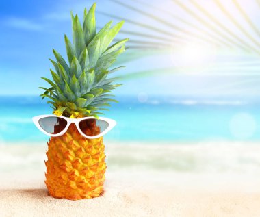 Tropik plaj arka planında güneş gözlüklü ananas. Yaz konsepti.