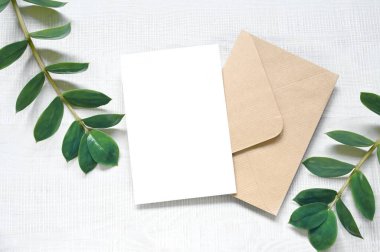 Kartı bitkilerle süsleyin. Beyaz arkaplanda zarf olan davet kartı