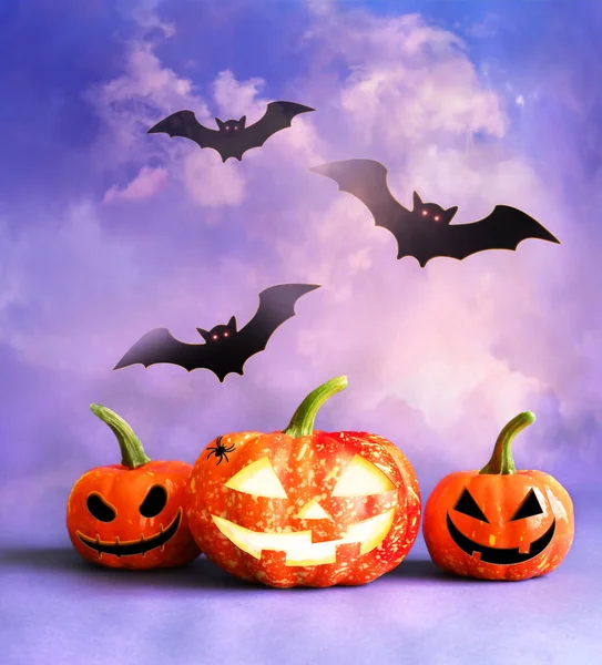 Halloween pumpkin head jack lantern with burning candles and black bats. Halloween concept.