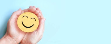 Hand holding happy smile face on blue background, Positive thinking, Mental health, World mental health day concept