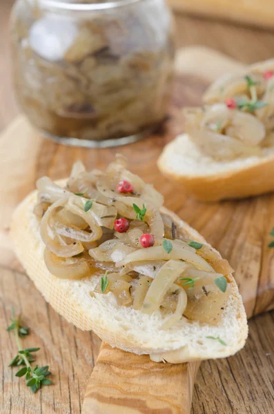 Confit of caramelized shallots on a piece of baguette closeup — Stock Photo, Image