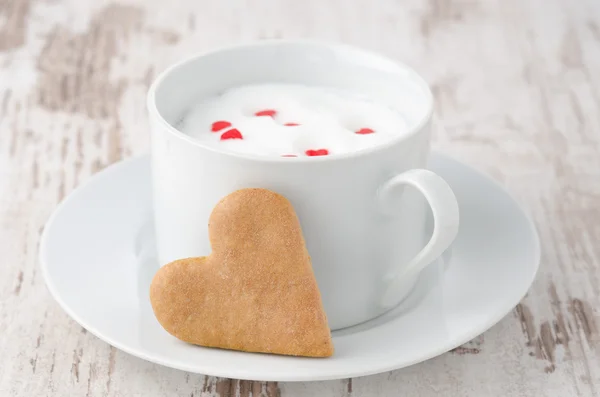 Taza de leche caliente con espuma y galletas en forma de corazón — Foto de Stock