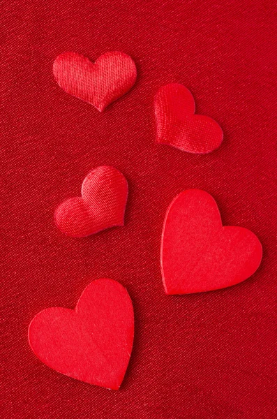 Hjärtan i olika storlekar på en röd bakgrund — Stockfoto