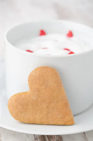 Cup of hot milk with foam, decorated with sugar hearts and heart — Stock Photo, Image