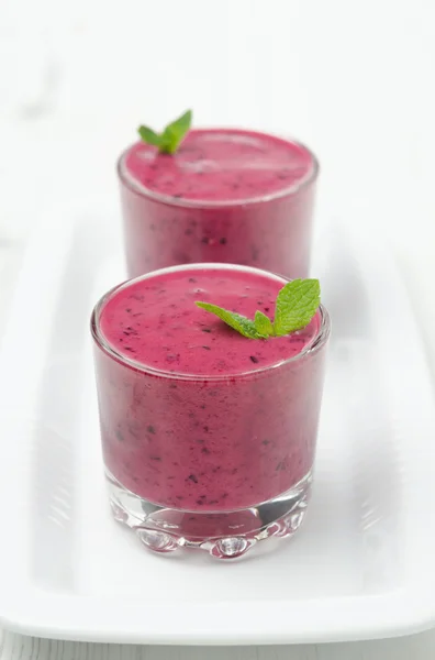 Smoothie de mirtilo com casa da moeda em um copo de vidro em uma chapa branca — Fotografia de Stock