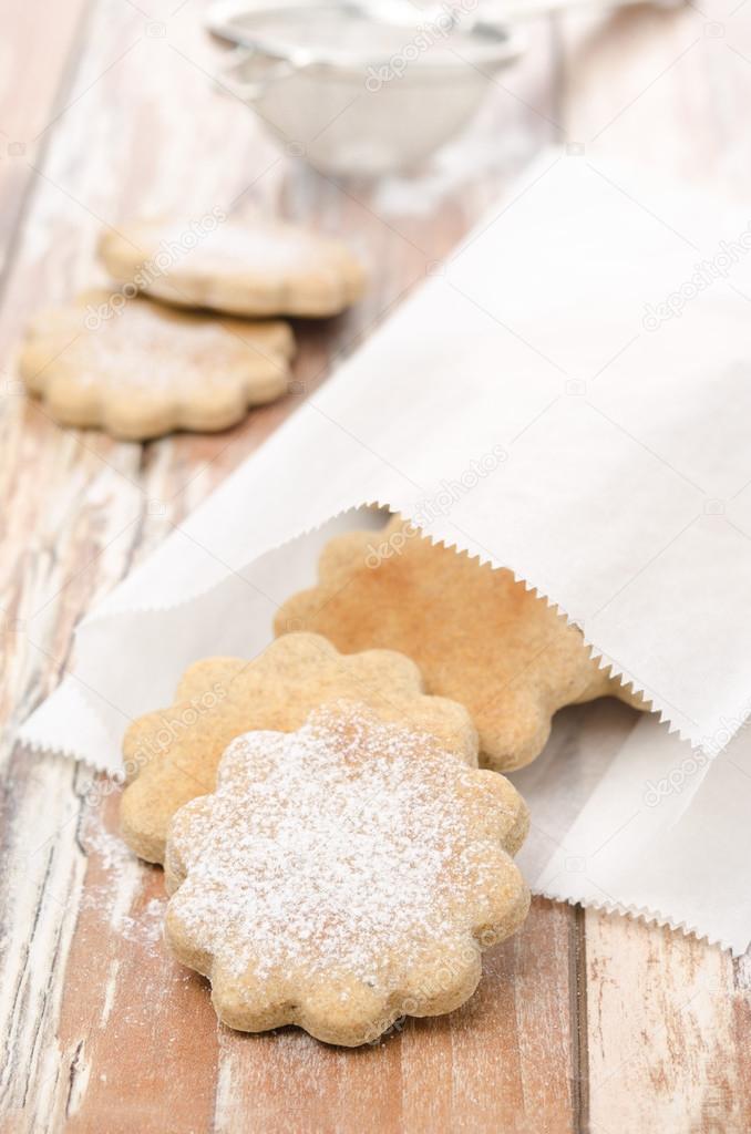 figured cookies sprinkled with powdered sugar in a paper bag