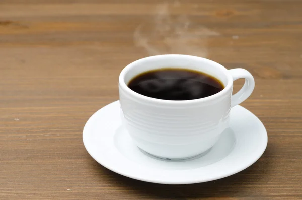 Tasse schwarzen Kaffee mit Dampf auf einem braunen Holztisch — Stockfoto