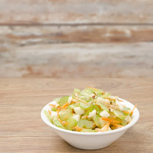 Salade met selder, wortelen en appels in een witte kom — Stockfoto