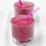 Blaubeer-Smoothie im Glasbecher auf weißem Teller