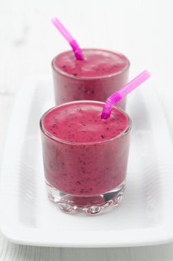 Beyaz bir plaka üzerinde bir cam kabı içinde Blueberry smoothie