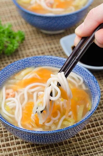 Chinese soup with noodles and vegetables and hand with chopstick — Stock Photo, Image