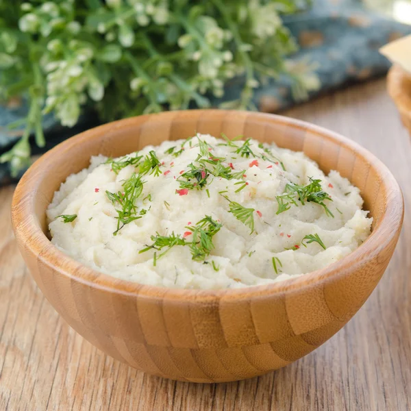 Wooden bowl of mashed potatoes topped with green — Stock Photo, Image