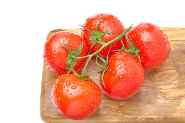 Branch of fresh tomatoes on wooden board isolated on white — Stock Photo, Image
