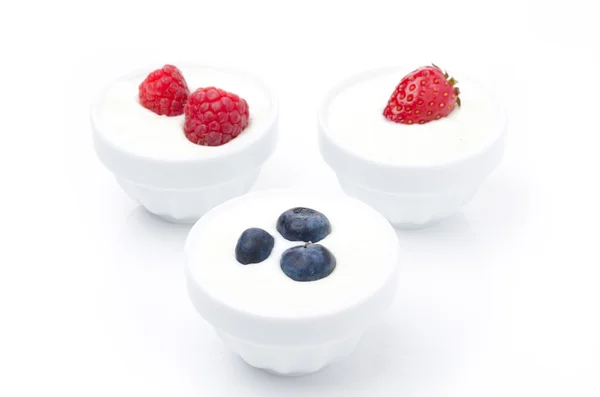 Joghurt mit verschiedenen frischen Beeren in Schalen auf weiß — Stockfoto