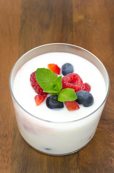 Iogurte com diferentes bagas e hortelã em um copo de vidro — Fotografia de Stock