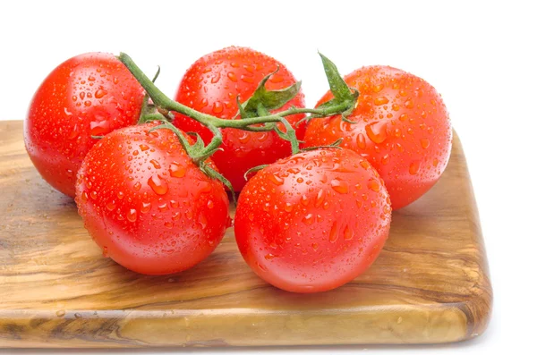 Fresh tomatoes on a branch on a wooden board isolated — Stock Photo, Image