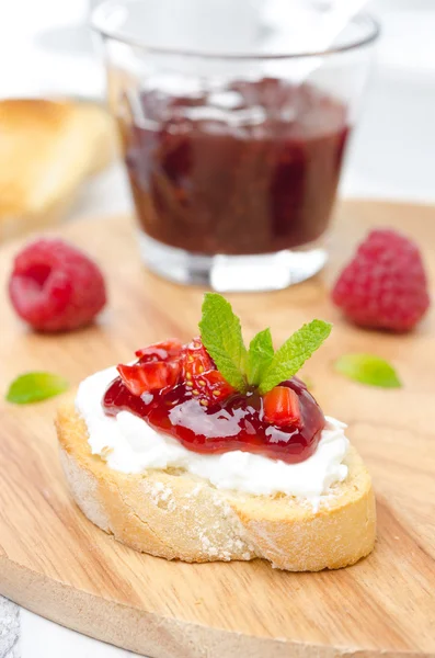 Piece of toasted baguette with cream cheese, raspberry jam
