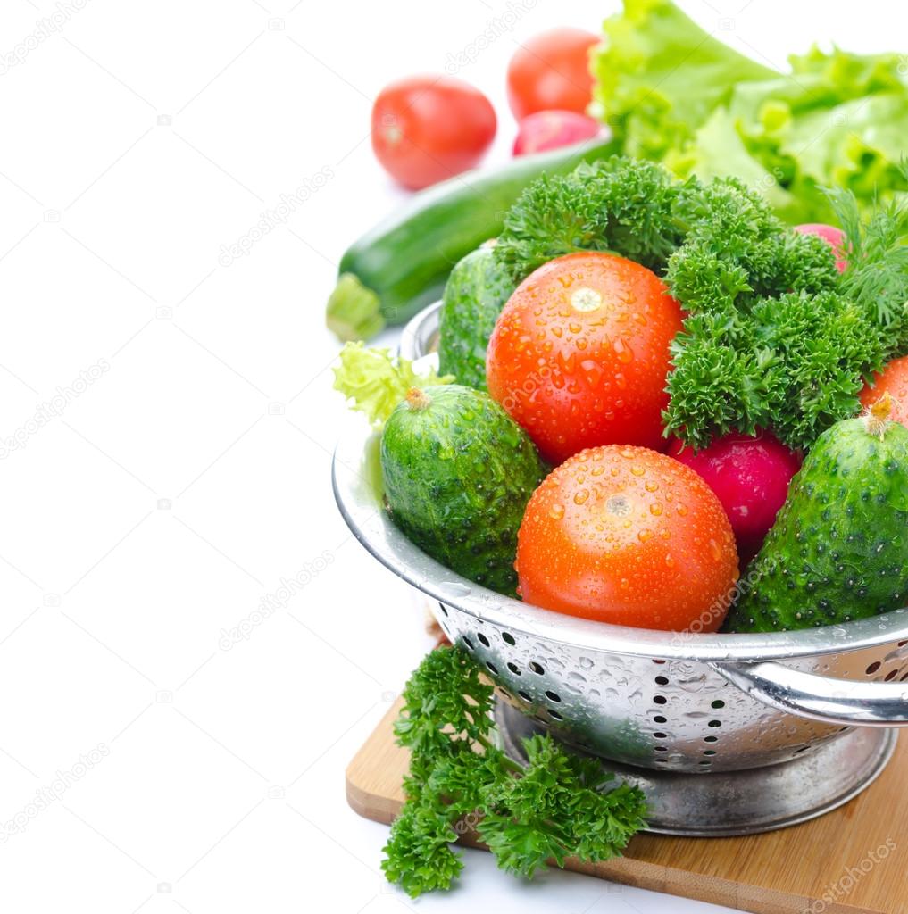 Fresh vegetables and herbs in metal colander, isolated