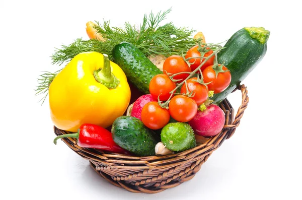 Assorted fresh vegetables and herbs in a wicker basket on white — Stock Photo, Image