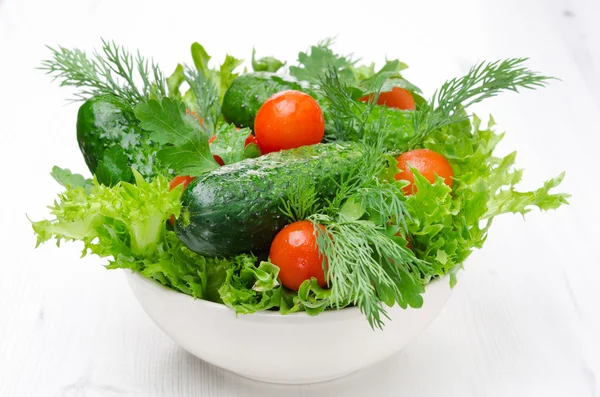 Cuenco con verduras frescas y hierbas para ensalada en un blanco —  Fotos de Stock