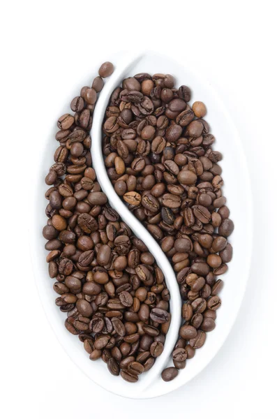 Granos de café en un plato blanco en forma de grano — Foto de Stock