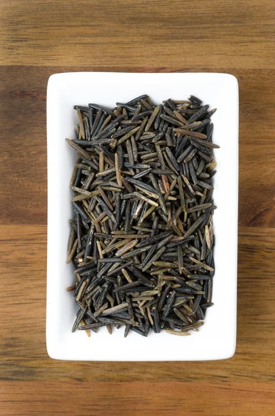 Wild rice in a white bowl on wooden background — Stock Photo, Image