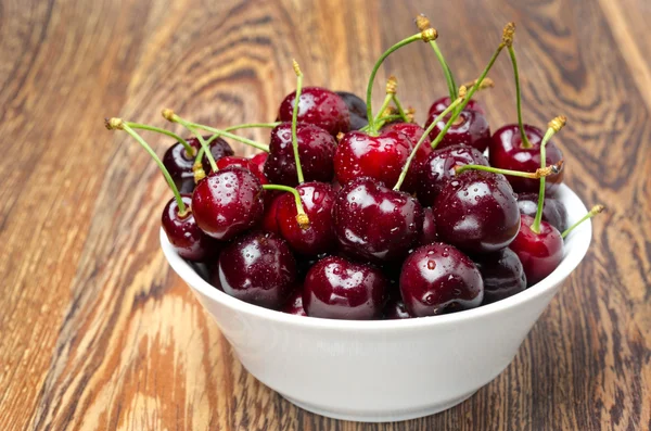 Bowl of fresh cherries on a wooden background, close-up — Stock Photo, Image
