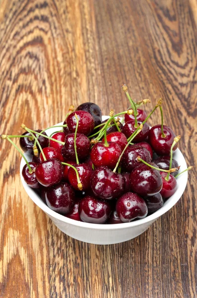 Bowl of fresh cherries on a wooden background, top view — Stock Photo, Image
