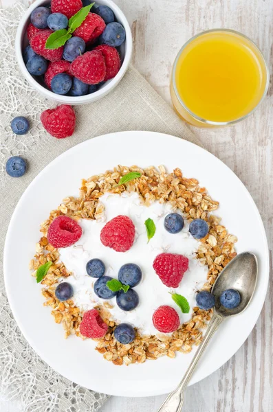 Zelfgemaakte muesli met yoghurt, verse bessen en een glas van Oranje — Stockfoto