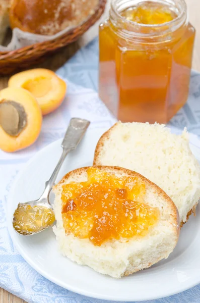 Sweet bun with apricot jam on a plate — Stock Photo, Image