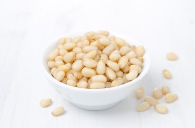 beyaz zemin üzerinde bir kasede çam fıstığı