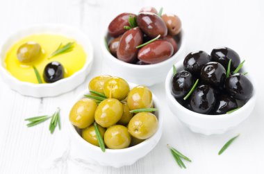 üç çeşit zeytin kaseler, taze biberiye ve zeytin yağı