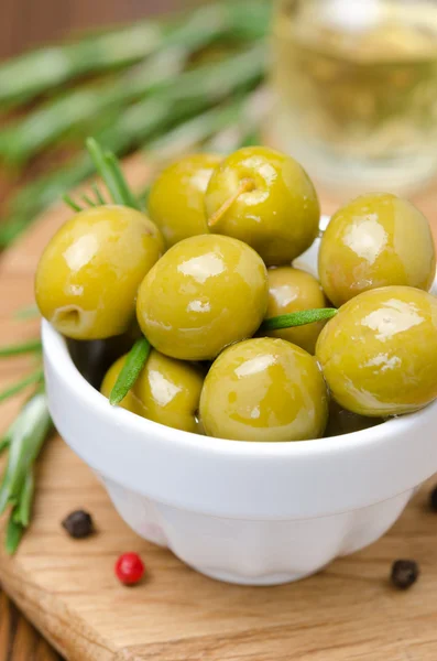 Groene olijven en specerijen op een houten bord, close-up verticaal — Stockfoto