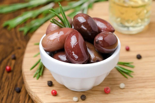 Kalamata olijven en specerijen op een houten bord — Stockfoto