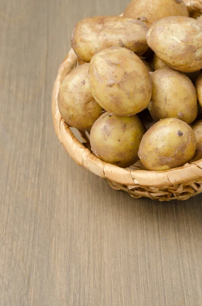 Patatas en una canasta sobre un fondo gris de madera —  Fotos de Stock