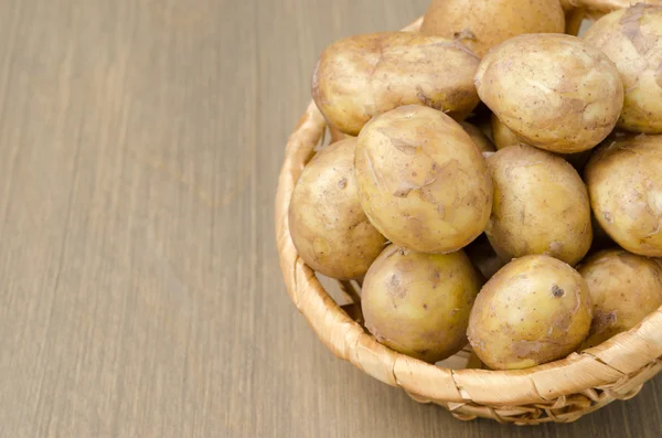 Papas nuevas en una cesta sobre un fondo de madera gris —  Fotos de Stock