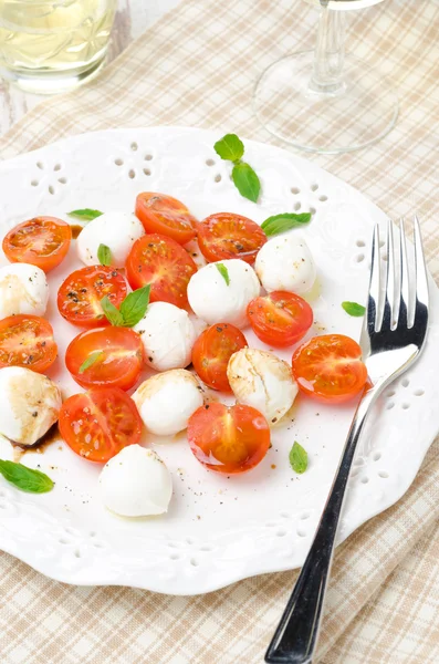 Salade met mini mozzarella, tomaten en verse basilicum op een plaat — Stockfoto