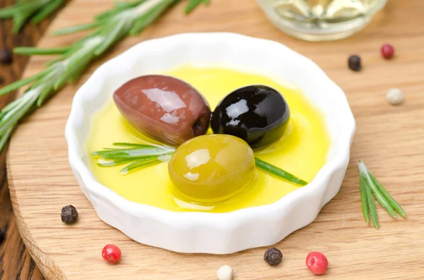 Three kinds of olives and fresh rosemary in a bowl — Stock Photo, Image