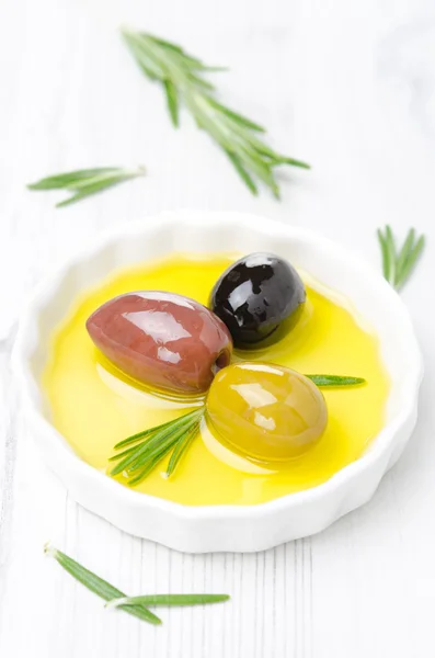 Tres tipos de aceitunas y romero en un tazón con aceite de oliva — Foto de Stock