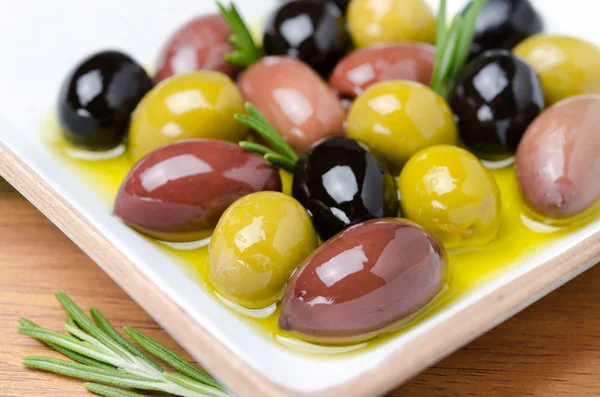 Vit träskål med en mängd oliver och rosmarin i olja — Stockfoto